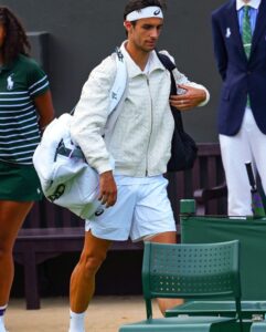 Lorenzo Musetti arriving at Wimbledon wearing a white Bottega Veneta intrecciato bomber jacket, carrying tennis bags, and exuding understated Italian elegance