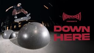 A skateboarder from the Independent Trucks “DOWN HERE” tour in Australia performing a high-speed trick on a sculptural concrete ledge at night, surrounded by an urban backdrop, capturing the raw and rebellious spirit of the tour