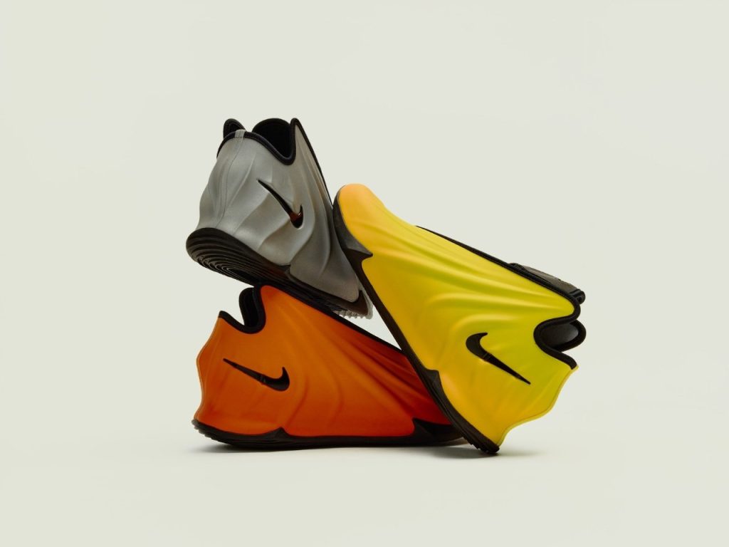 Three futuristic Nike G.T. Future basketball shoes in gradient grey, orange, and yellow colorways, stacked in an artistic, sculptural arrangement showcasing their sleek, aerodynamic design