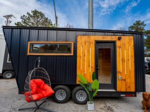 Dragon Tiny Homes sauna-on-wheels with black metal exterior, warm wood accents, and minimalist Scandinavian design