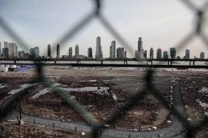 View of a fenced vacant lot with debris in Manhattan, New York City, with skyscrapers in the background, representing potential casino development sites