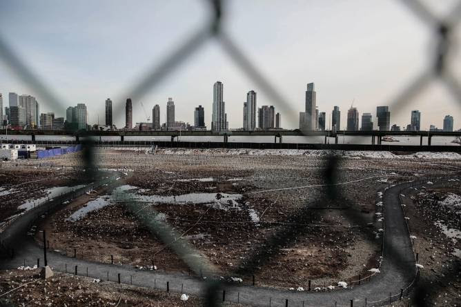 View of a fenced vacant lot with debris in Manhattan, New York City, with skyscrapers in the background, representing potential casino development sites