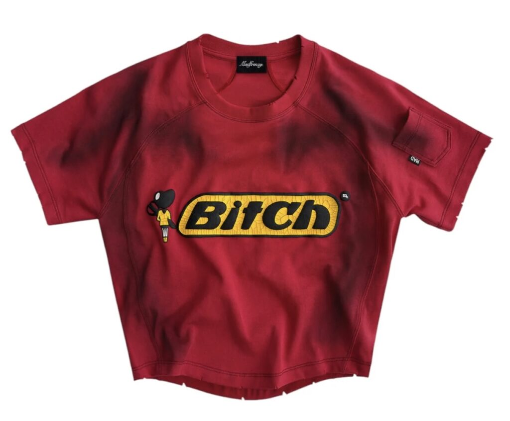 Red MADFRENZY ‘Bitch’ Tee with bold yellow cracked chest patch and raised black lettering, featuring a small cartoon-style female figure beside the logo.