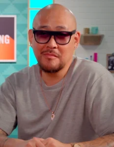 Ben Baller wearing sunglasses and a gray T-shirt, seated indoors during a media appearance, 2025.