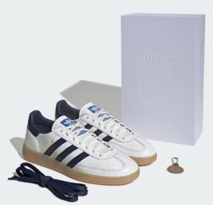 Adidas Spezial “Made in Germany” sneakers in white leather with navy stripes and gum sole, displayed with a premium white embossed box, extra navy laces, and a Trefoil keychain.