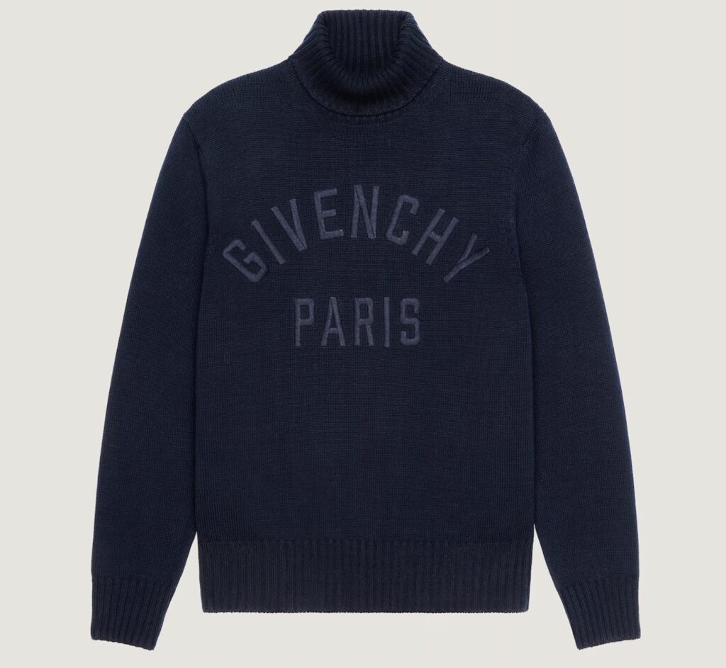“New Givenchy cotton turtleneck sweater in black featuring bold white GIVENCHY Paris embroidery across the chest, minimalist silhouette with high ribbed collar, photographed against a plain background.”
