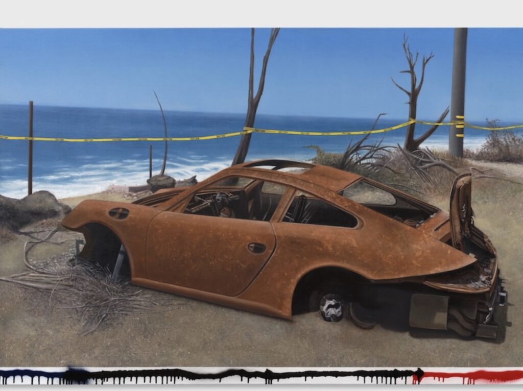 A rusted, fire-damaged Porsche sits abandoned on a sandy cliffside overlooking the ocean, surrounded by yellow caution tape and charred trees, symbolizing loss and resilience in Alfonso Gonzalez Jr.’s NO PARKING exhibition.