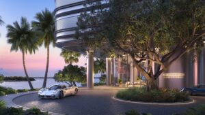 Exterior view of Pagani Residences in Miami, featuring a silver Pagani hypercar parked under palm trees at sunset, with the building’s perforated aluminum façade and illuminated Pagani logo visible.