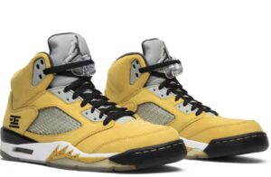 A pair of Air Jordan 5 “Tokyo” sneakers featuring bold Varsity Maize suede uppers, Wolf Grey tongues, black midsoles with speckled shark teeth, and the distinctive kanji-style “23” logo stitched on the heel.