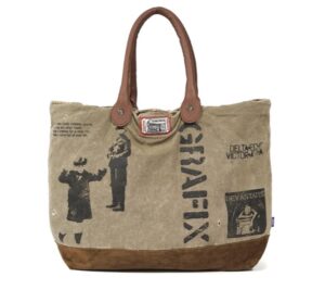 DEVA STATES SS25 Tote Bag ‘Canvas’ featuring khaki canvas body with bold black graphic prints, brown suede base, and leather handles, blending rugged utility with rebellious streetwear edge.