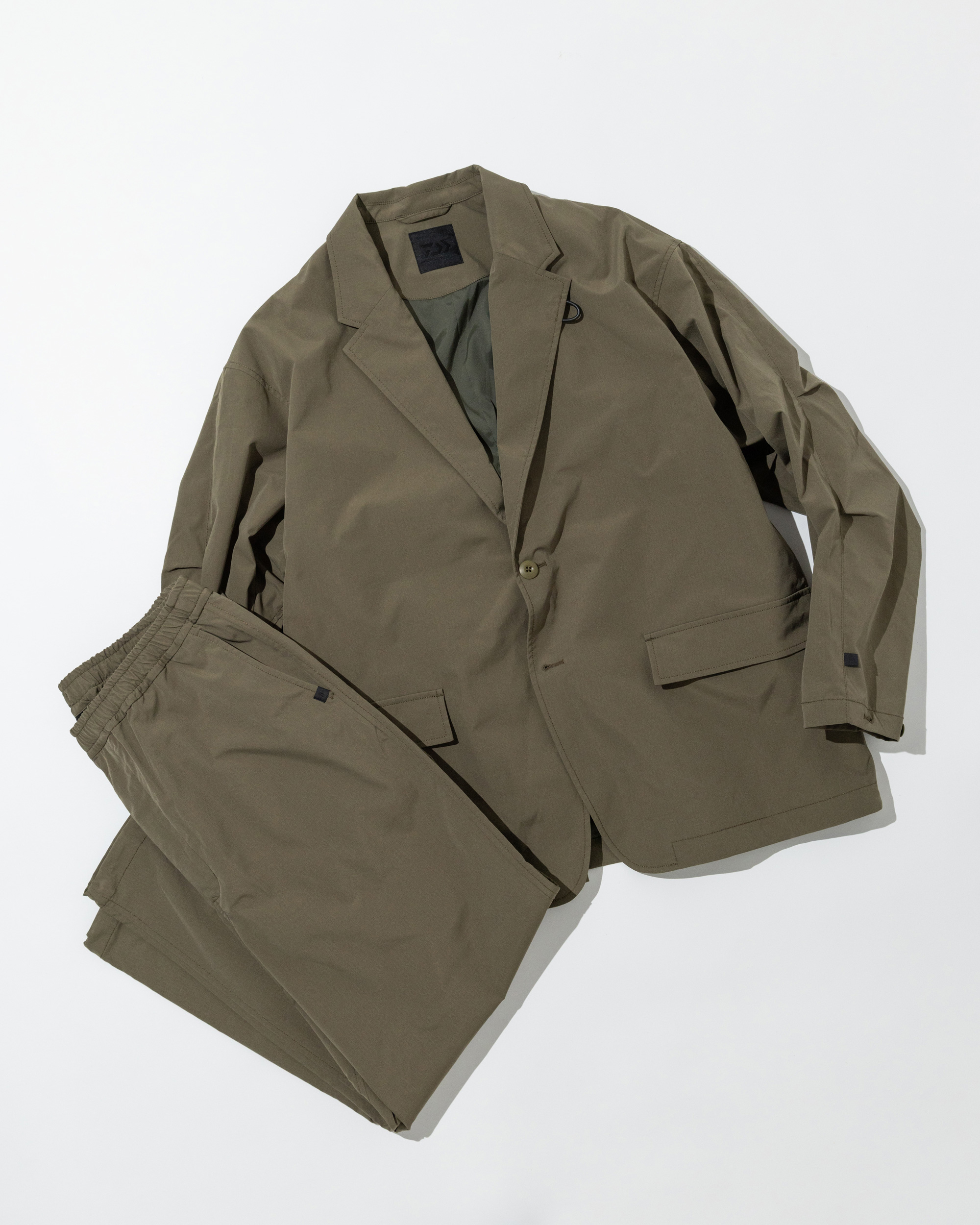 Olive green DAIWA PIER39 TECH LOOSE 2B JACKET paired with matching ripstop pants, a technical two-piece set blending outdoor durability with urban tailoring.