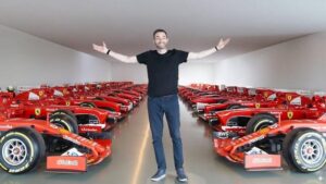 Former F1 driver Scott Mansell stands with arms outstretched inside Ferrari’s secret Formula 1 bunker, surrounded by rows of historic scarlet Ferrari race cars