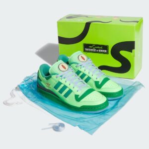 The Simpsons x adidas Forum Low “Treehouse of Horror: Kang & Kodos” sneakers in shades of green with alien eye tongue design, displayed with themed green box, blue drawstring bag, and eyeball lace accessory.