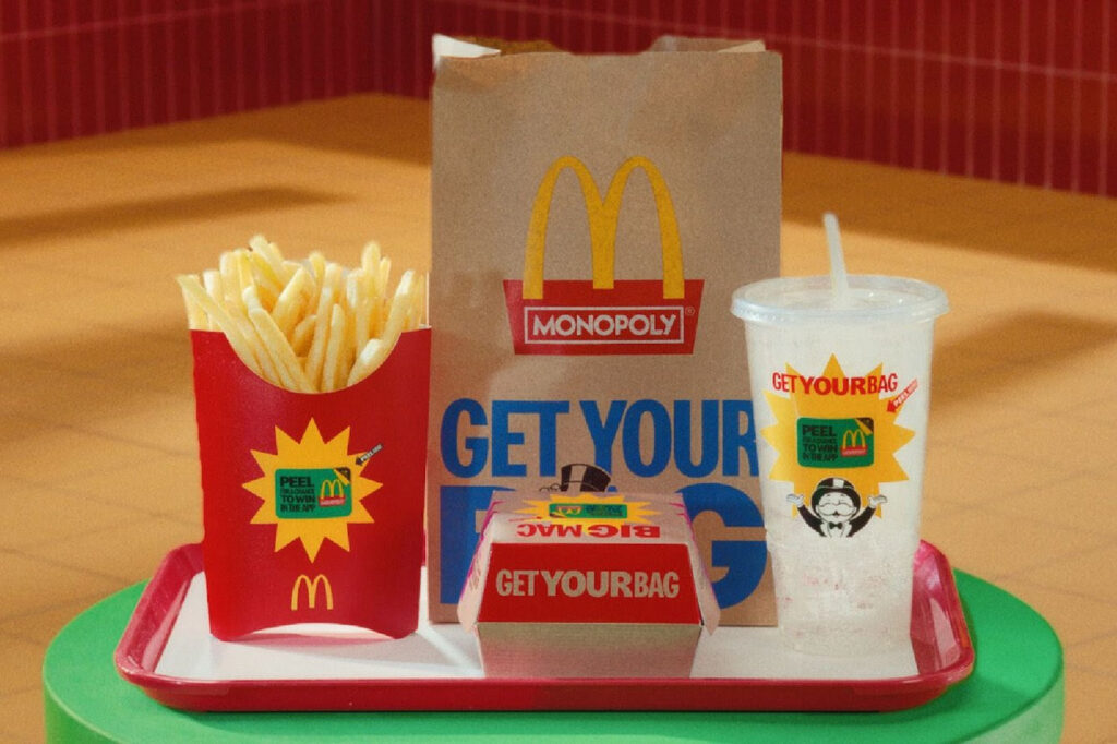 McDonald’s Monopoly promotion meal set with fries, Big Mac box, soft drink, and paper bag featuring Monopoly branding and “Get Your Bag” slogan on a tray.