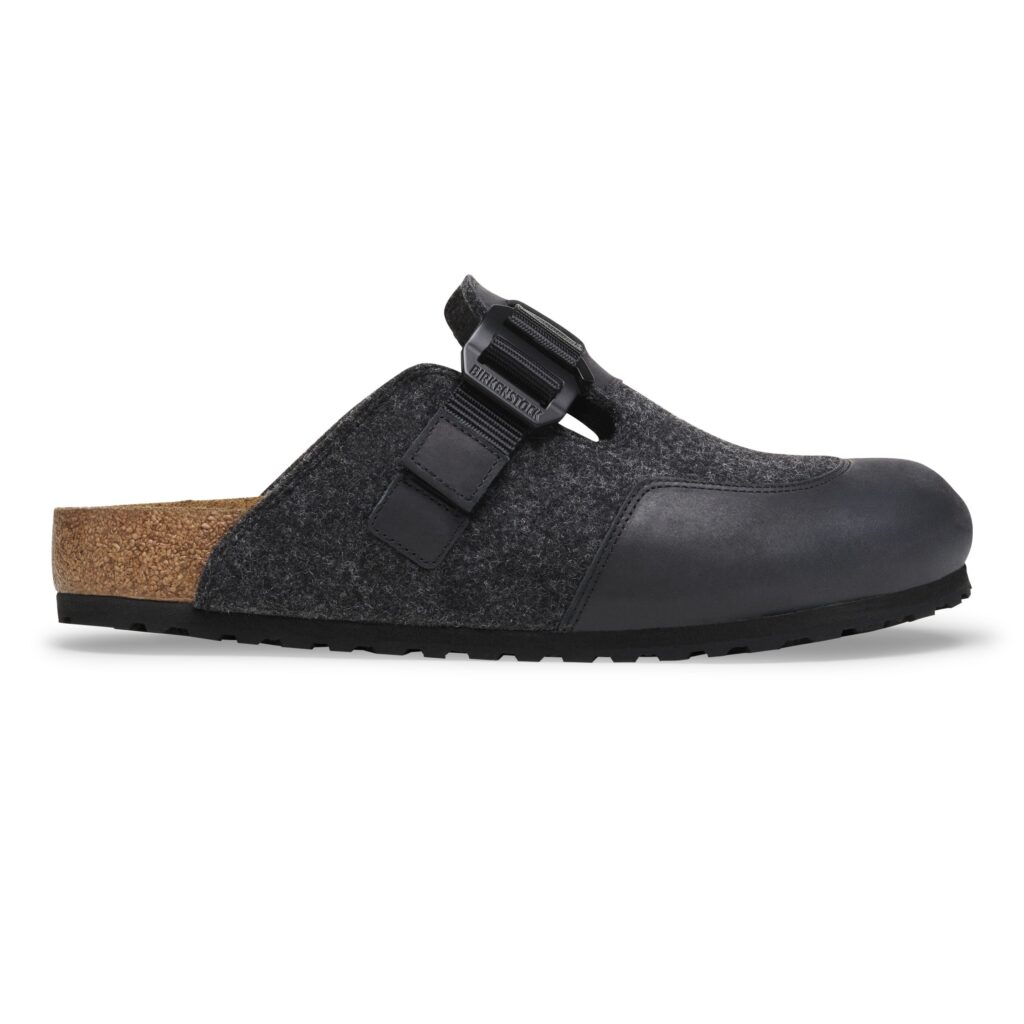 Side profile of the BIRKENSTOCK Boston clog from the Utility Felt Pack in Anthracite. The clog features a dark wool felt upper with a smooth black leather toe-cap, adjustable nylon strap with rustproof G-hook buckle, and a natural cork-latex footbed. The black EVA outsole completes the minimalist, winter-ready design that merges workwear-inspired durability with timeless comfort.
