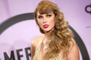 Taylor Swift. posing against a pink and purple backdrop at an awards event.