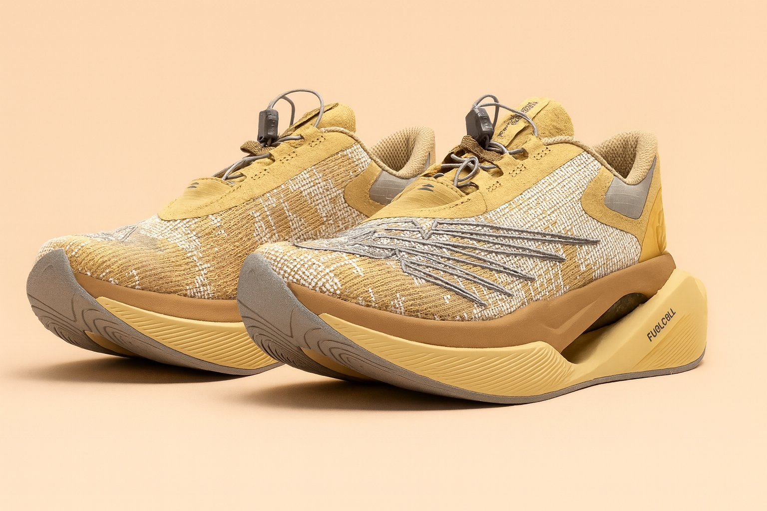 New Balance × Stone Island Tokyo Design Studio FuelCell C_1 sneakers displayed on a soft peach background, highlighting their tan and beige knit upper, sculpted midsole, and magnetic speed-lacing system