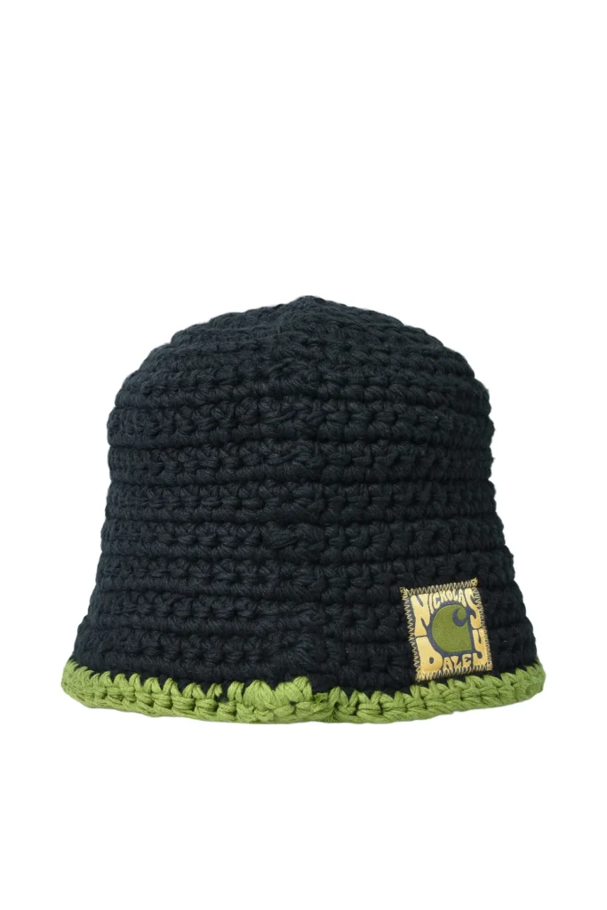 Hand-crocheted bucket hat from the Carhartt WIP × Nicholas Daley Fall/Winter 2025 collection, featuring deep navy yarn with a contrasting olive-green trim and a woven Nicholas Daley logo patch stitched at the front brim.