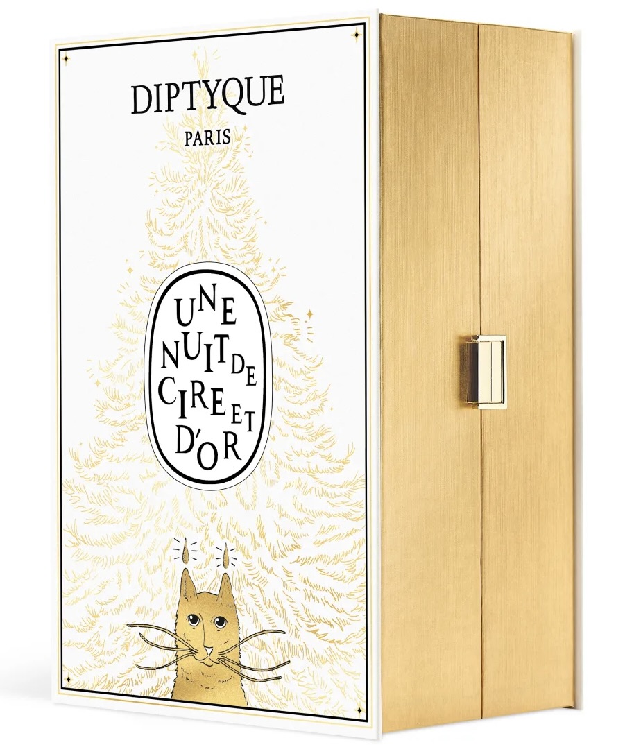 Diptyque Paris “Une Nuit de Cire et d’Or” Advent Calendar 2025 box featuring a gold and white design with an illustrated cat beneath a stylized fir tree, housed in a gold cabinet-style case with a metallic clasp.