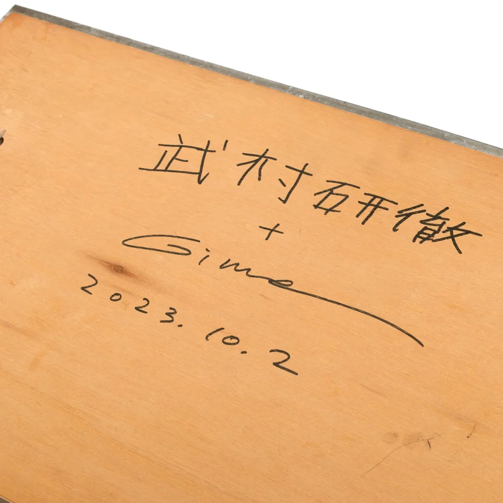 close-up of a wooden surface signed by tomotatsu gima with japanese characters, a handwritten signature, and the date 2023.10.2 written in black ink, representing the artist’s collaboration marking.