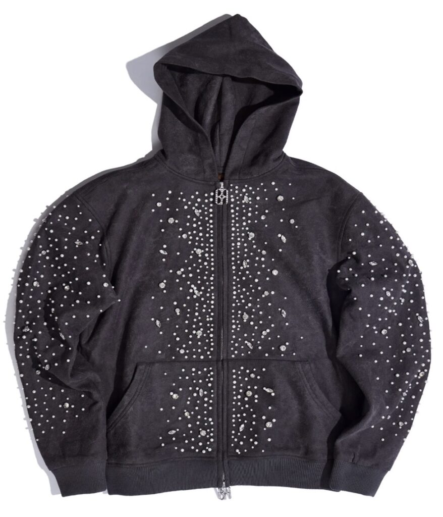 A charcoal-grey zip-up hoodie adorned with clusters of pearl and crystal embellishments across the sleeves, chest, and torso. The jewels form an intricate, star-like pattern that catches light against the soft suede-textured fabric, giving the garment a celestial, regal appearance.