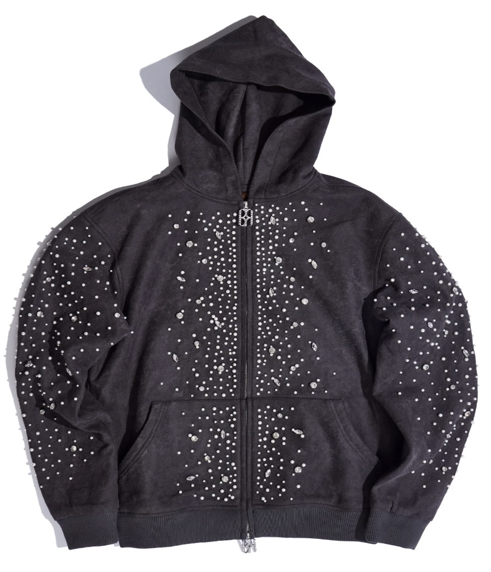 A charcoal-grey zip-up hoodie adorned with clusters of pearl and crystal embellishments across the sleeves, chest, and torso. The jewels form an intricate, star-like pattern that catches light against the soft suede-textured fabric, giving the garment a celestial, regal appearance.