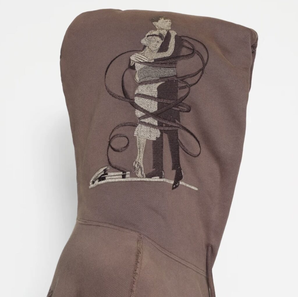 Close-up of brown hoodie hood featuring an embroidered design of a man and woman embracing, wrapped in looping film reels, symbolizing classic cinema romance.