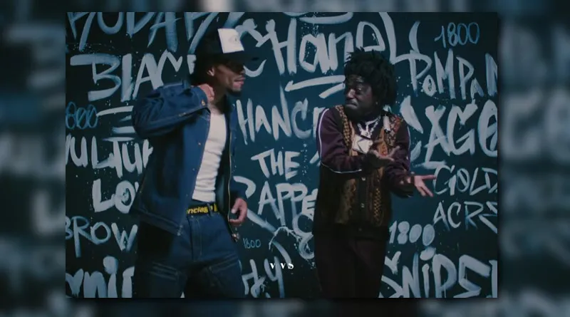 Kodak Black and Chance the Rapper perform side by side in front of a graffiti wall featuring the words “Chanel,” “Chance the Rapper,” and “Pompano.” Kodak wears a vintage-style brown tracksuit and layered jewelry, while Chance sports a denim jacket, white tee, and trucker hat — capturing a blend of street luxury and artistic self-expression that mirrors the theme of Still Get Chanel.