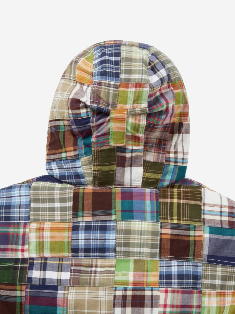 Rear view of the thisisneverthat AW25 Washed Down Puffer Jacket Multi, highlighting the hood and upper back covered in multicolored plaid patchwork patterns featuring greens, blues, oranges, and browns stitched together in a grid layout.