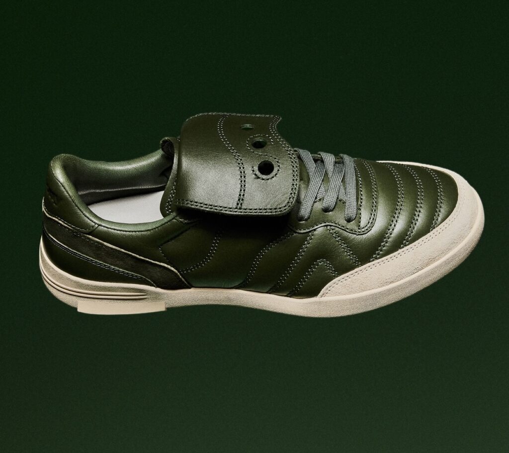 Saucony SILO Fall/Winter 2025 sneaker in deep pine green leather with tonal stitching, suede toe guard, and parchment midsole, photographed against a dark green backdrop.