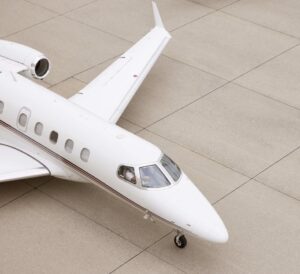 A white NetJets private jet positioned on the tarmac, photographed from above, showcasing the cockpit, wing, and sleek fuselage.