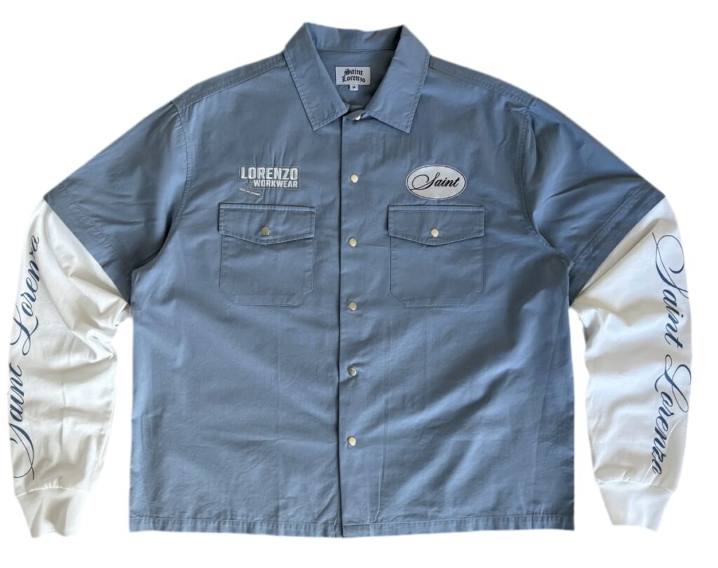 Saint Lorenzo Workwear Blue Shirt in deep mineral blue cotton twill, displayed folded neatly on a stone surface with visible topstitching and reinforced seams, symbolizing refined utility and contemporary craft.