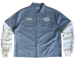 Saint Lorenzo Workwear Blue Shirt in deep mineral blue cotton twill, displayed folded neatly on a stone surface with visible topstitching and reinforced seams, symbolizing refined utility and contemporary craft.