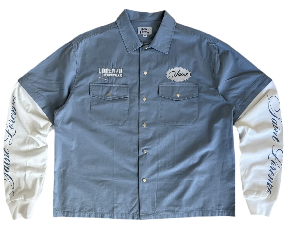 Saint Lorenzo Workwear Blue Shirt in deep mineral blue cotton twill, displayed folded neatly on a stone surface with visible topstitching and reinforced seams, symbolizing refined utility and contemporary craft.