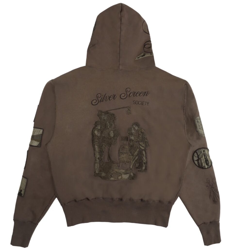 Back view of brown zip hoodie featuring embroidered “Silver Screen Society” lettering and a detailed scene of a vintage film crew operating a camera, evoking classic cinema aesthetics.