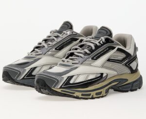 Pair of Reebok Premier Road Ultra Tonal Grey sneakers featuring layered mesh and leather panels in shades of grey, black, and beige, with a sculpted DMX Ride midsole and Reebok Vector logo on the side, photographed on a white background.