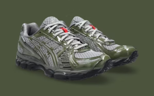 ASICS GEL-KAYANO 12.1 “Natsukashii” by UP THERE – photographed in three-quarter profile view, showcasing the grey mesh upper with glossy olive patent leather overlays, mint green accents, and Signal Red outsole details.