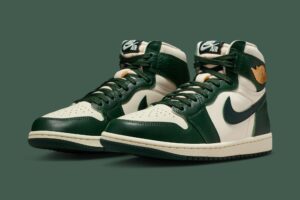 Air Jordan 1 High OG WMNS “Fir” — women’s high-top sneaker in smooth leather, featuring deep Fir Green overlays, Pale Ivory base panels, cream midsoles, and gold Wings logos, photographed against a matching green background.