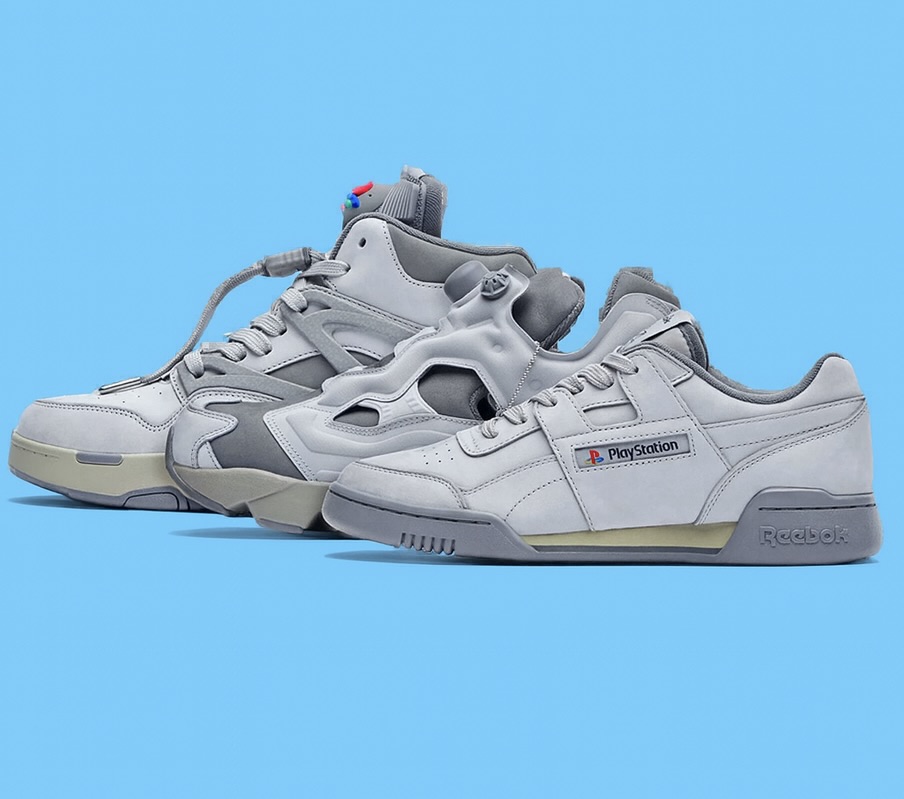 Reebok x PlayStation collab shoes displayed side by side on a medium sky blue background, featuring grey tones with subtle PlayStation branding and a mix of classic and futuristic design elements.