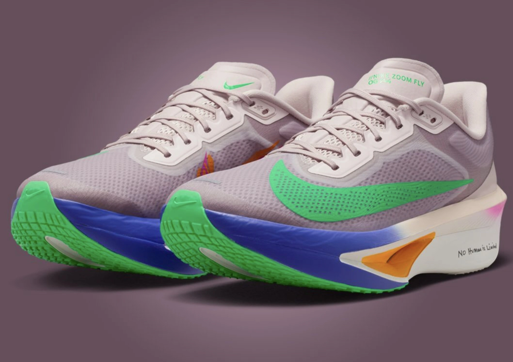 Close-up of the Nike Zoom Fly “No Human Is Limited” running shoes inspired by Eliud Kipchoge. The design features a beige mesh upper with a vivid green Swoosh, bright blue midsole, neon green outsole, and orange heel accent. The words “No Human Is Limited” are printed near the heel, symbolizing Kipchoge’s personal mantra. The shoes are displayed on a muted mauve background, emphasizing their vibrant contrast and aerodynamic shape.