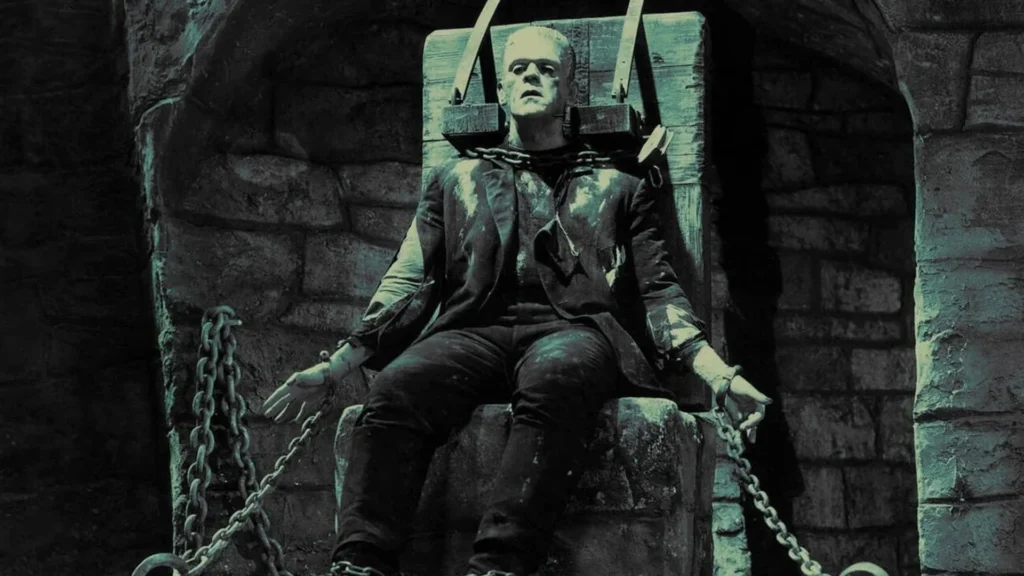 Classic black-and-white depiction of Frankenstein’s Monster strapped to a stone chair with chains, wearing torn clothes, from early Universal horror cinema.