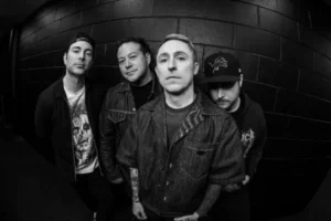 Black and white portrait of Yellowcard band members standing against a brick wall, captured in a moody fisheye perspective.