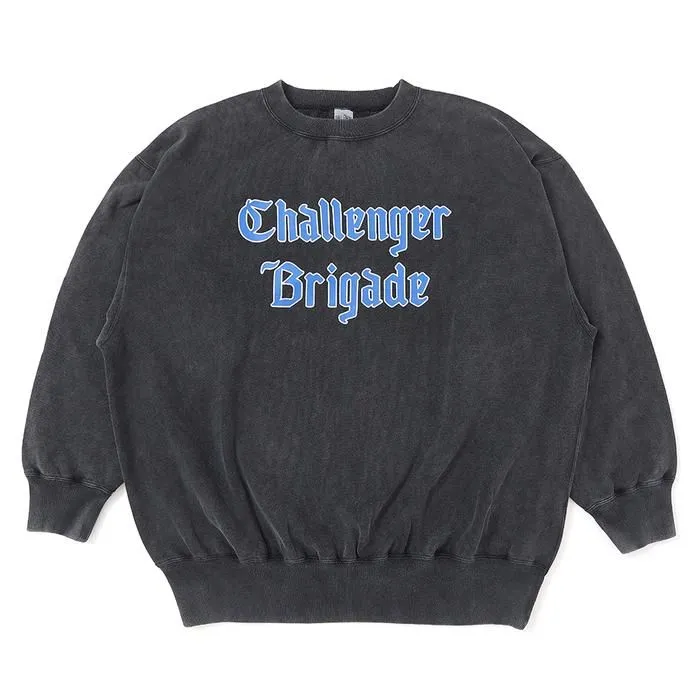 A washed black crewneck sweatshirt with ribbed cuffs and hem, featuring the words “Challenger Brigade” printed on the chest in bold light-blue Old English lettering