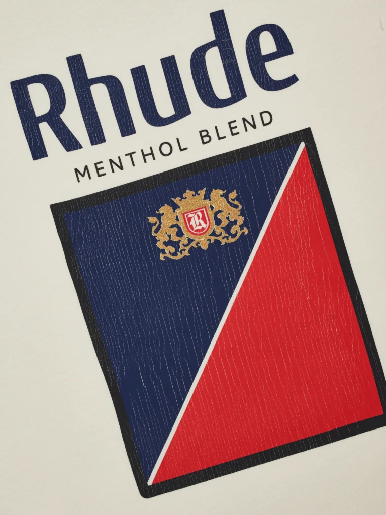 Close-up of the Rhude Collins Fumar Tee graphic showing the “Rhude Menthol Blend” logo with a navy and red split box design, gold crest detail, and fine cracking texture across the vintage-style print