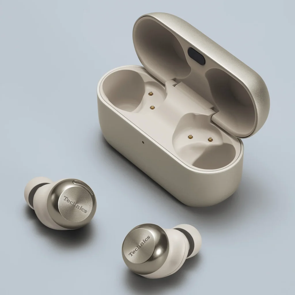 Technics EAH-AZ100 earbuds in Champagne Gold placed beside their open charging case on a soft blue surface, highlighting the earbuds’ metallic finish, ergonomic shape, and minimalist design aesthetic