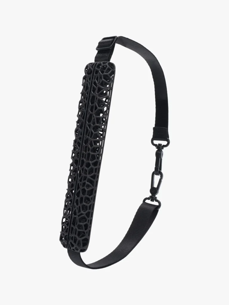 the cirrus strap from the aliveform × côte&ciel “living systems” collection, featuring a black adjustable shoulder strap with a 3d-printed lattice padding that resembles an organic cellular network, blending ergonomic design with futuristic structure