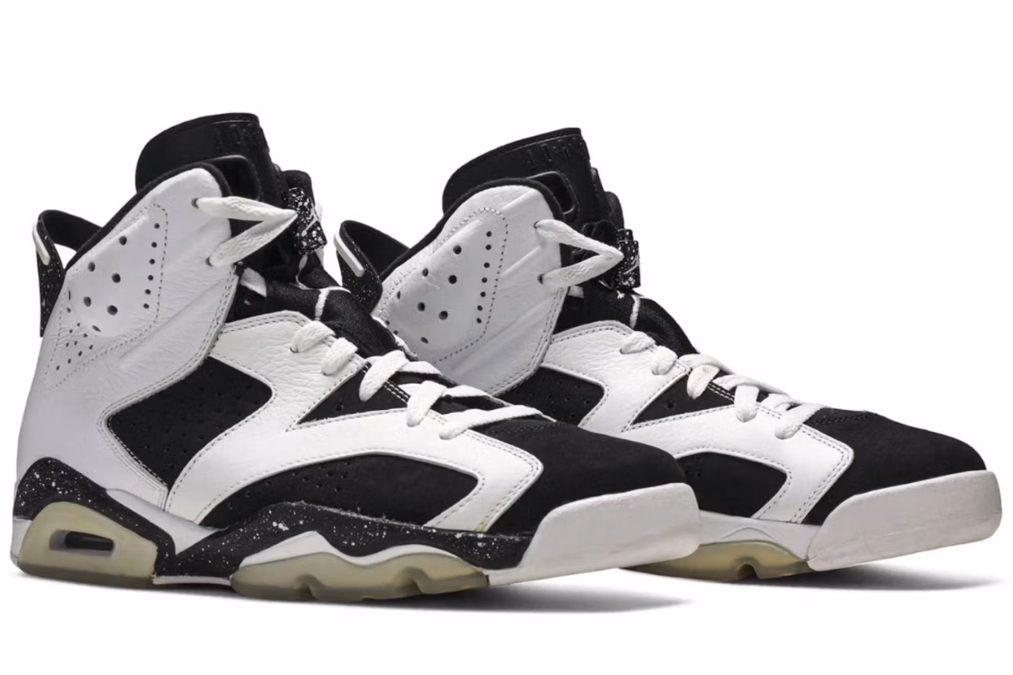 A close-up side view of the Air Jordan 6 “Oreo” sneaker, featuring a black nubuck upper with white leather overlays, a speckled black-and-white midsole, and an icy translucent outsole, photographed against a neutral backdrop