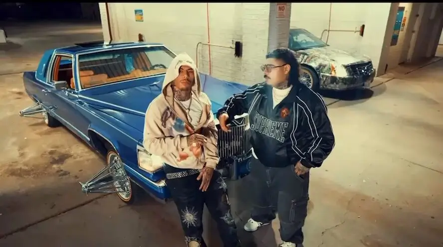 That Mexican OT wearing sunglasses and a black Supreme jacket sits outdoors at night holding a white styrofoam cup, while RNB.FOEMOB in a hooded sweatshirt stands behind him pointing toward the camera in a dimly lit rural setting