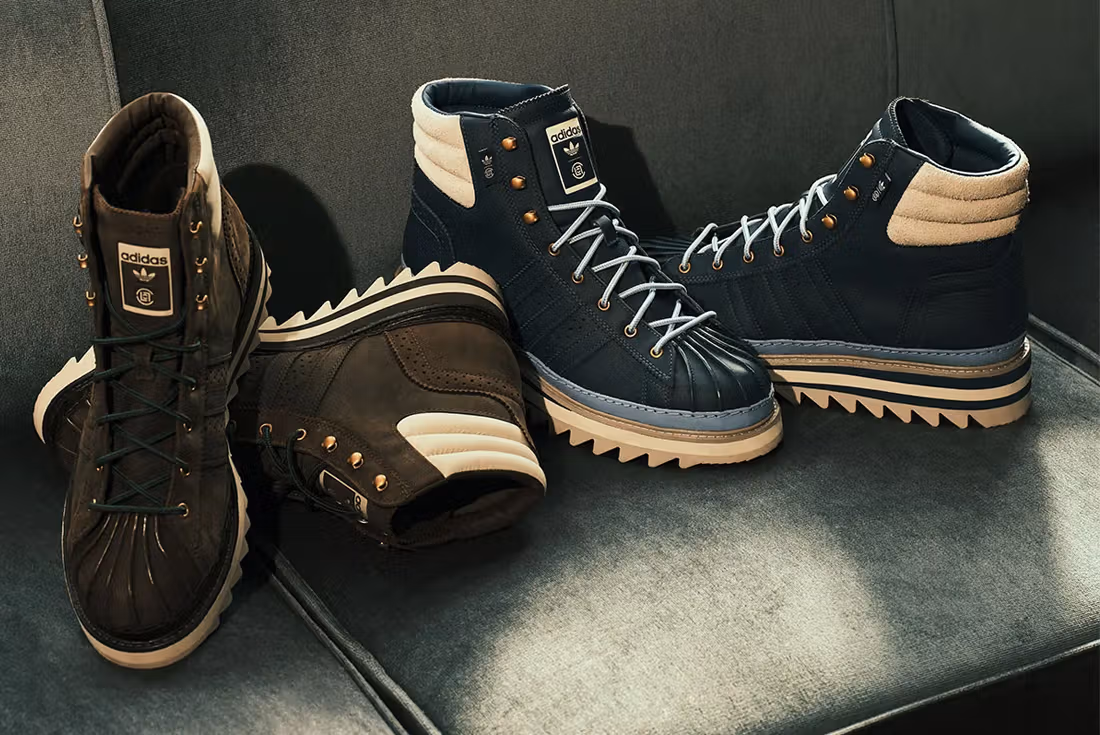 The CLOT x adidas Pro Model Winter Boot in dark brown leather with metal eyelets, rope laces, and a rugged tread outsole, photographed on a snowy concrete surface, showcasing its shell-toe design and cold-weather durability