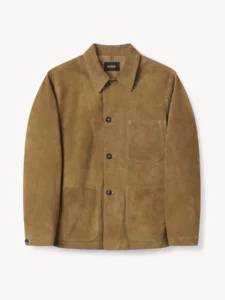 Buck Mason Rambler Suede Sportsman Jacket in heath brown steerhide suede, featuring a relaxed fit chore coat silhouette inspired by the 1941 USMC utility jacket. The jacket displays three front patch pockets, a pointed collar, and dark horn-style buttons, photographed against a clean white background to highlight its craftsmanship and rich suede texture